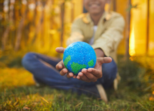 Young boy holds planet earth model in hands.