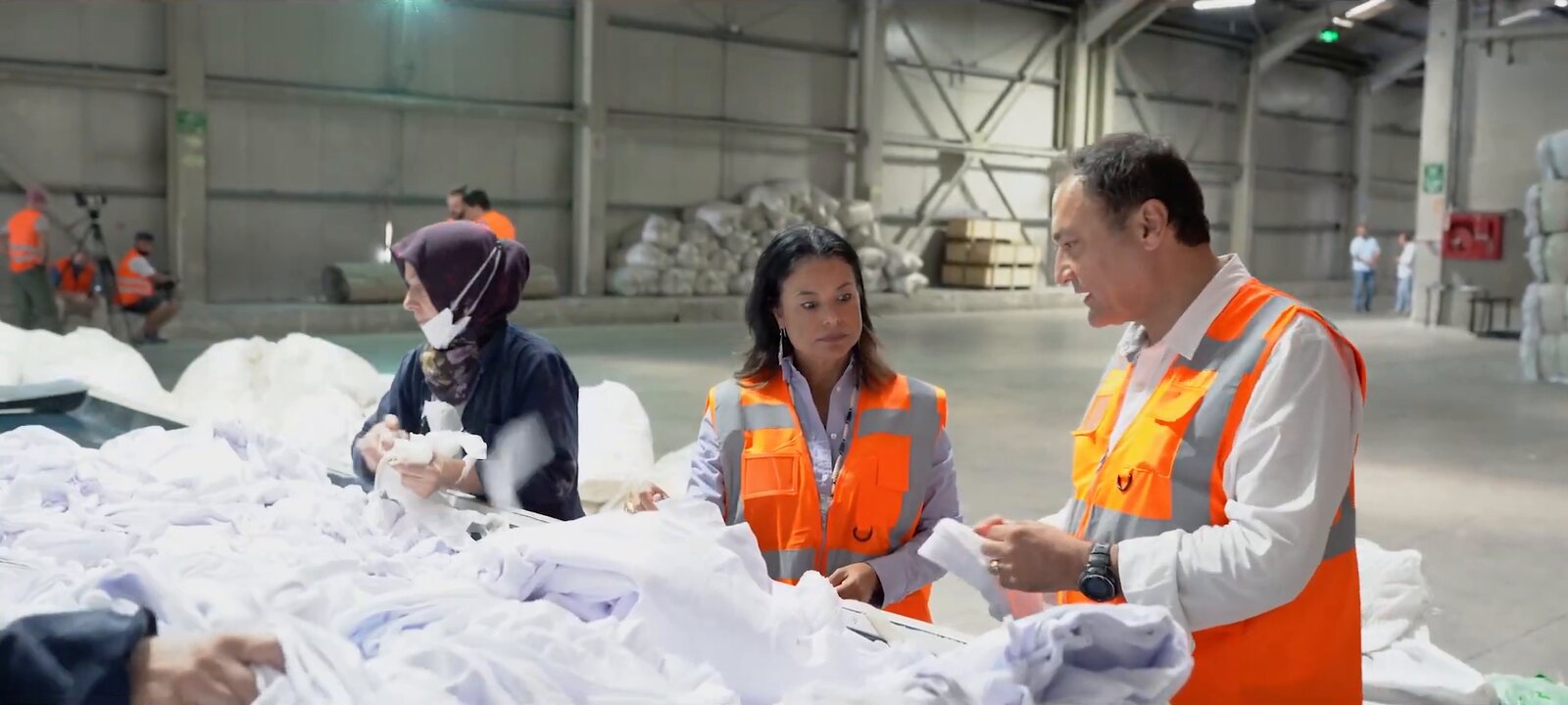 Charlene Nijmeh in a safety vest sorting donated clothing with recycling partners in a warehouse
