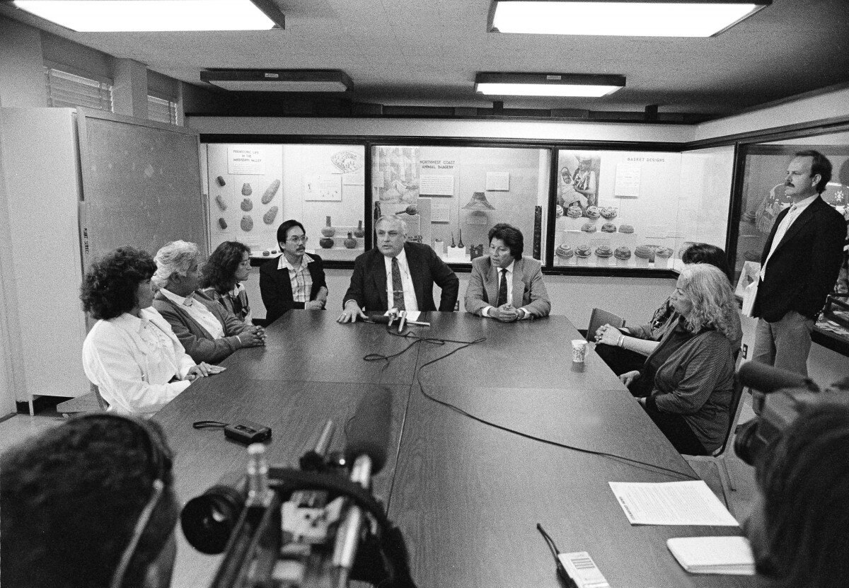 Black-and-white photo of Ohlone representatives and Stanford officials seated at a conference table during the 1990 transfer of ancestral remains