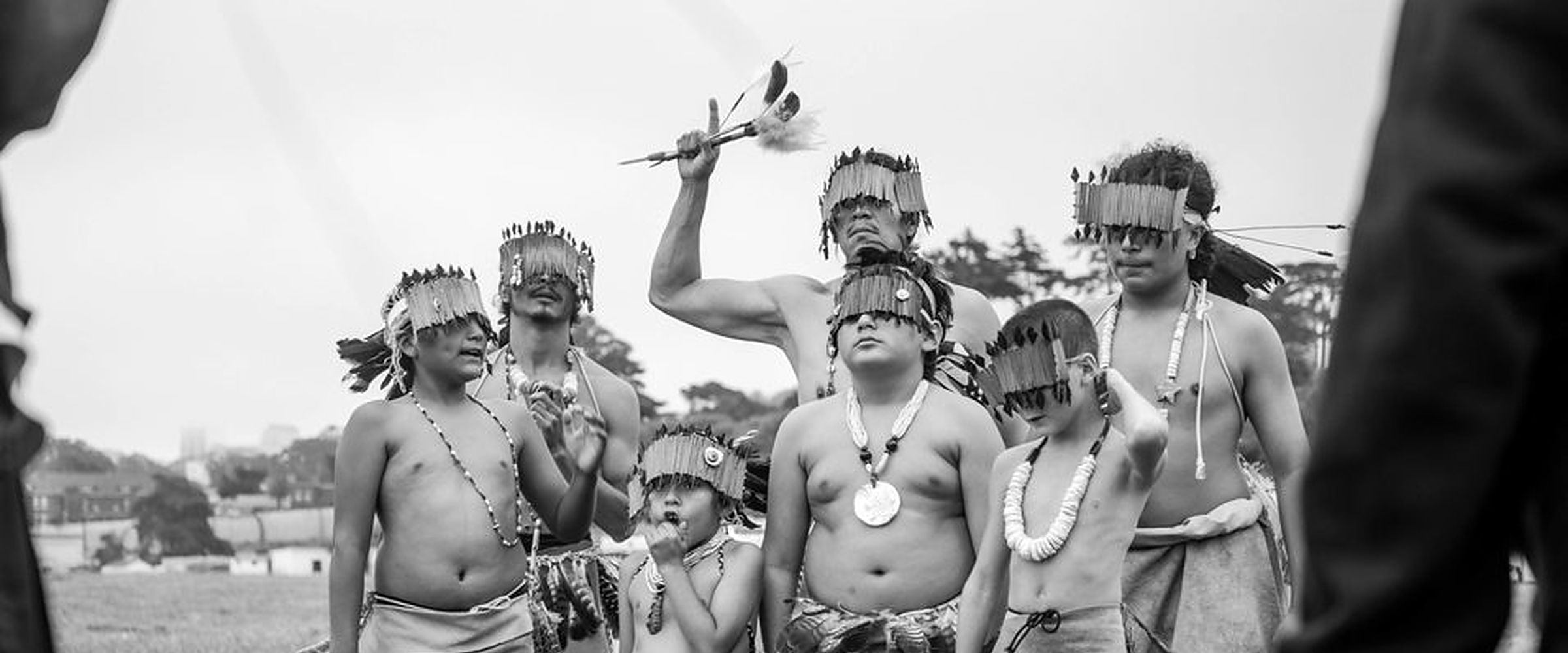 Muwekma Ohlone dancers in regalia gather on a grassy field in San Francisco