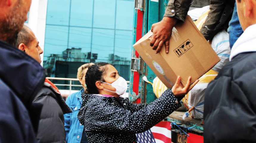 Relief boxes handed down from a truck to people waiting below