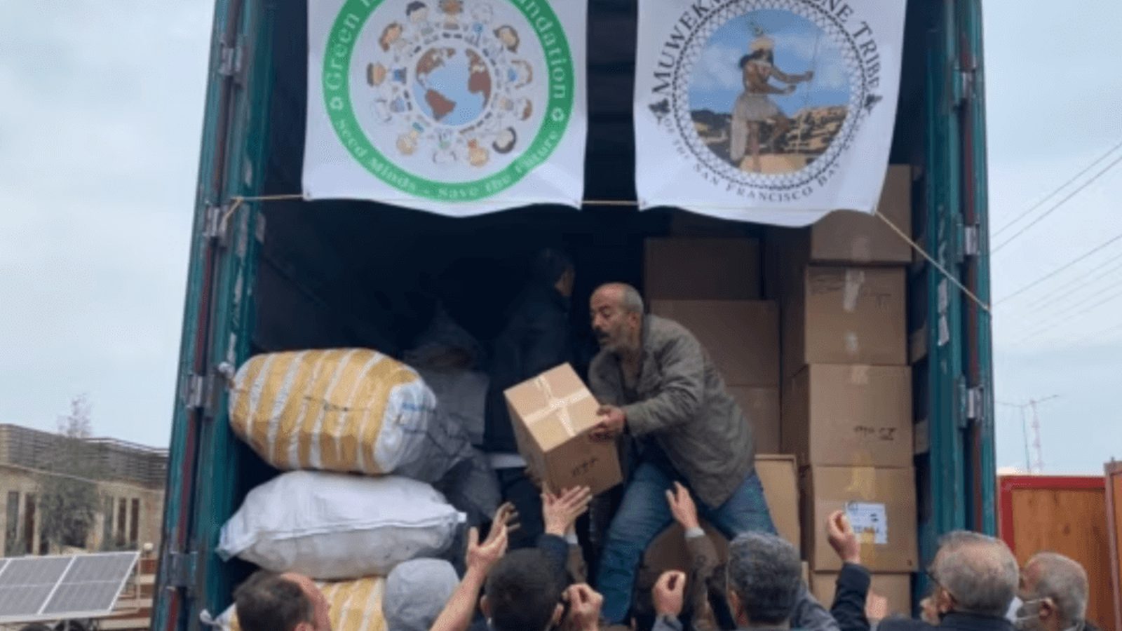 Volunteers unloading relief supplies from a truck hung with GEF and Muwekma Ohlone Tribe banners