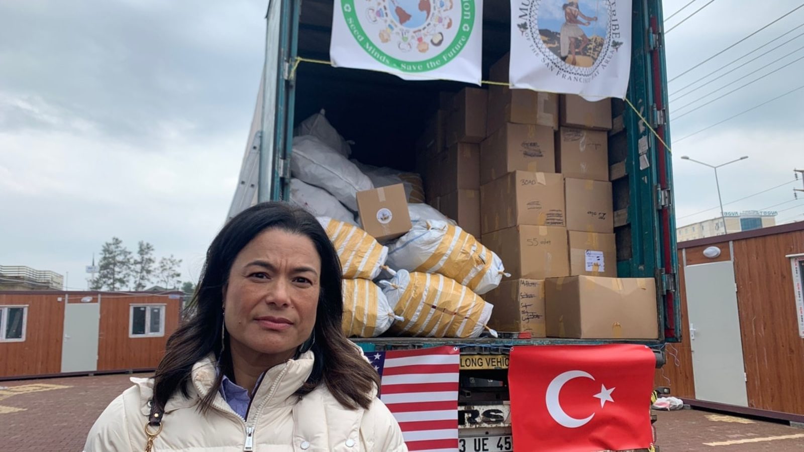 Charlene Nijmeh beside a truck of relief supplies, with U.S. and Turkish flags